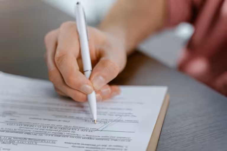 Person signing document with pen on clipboard