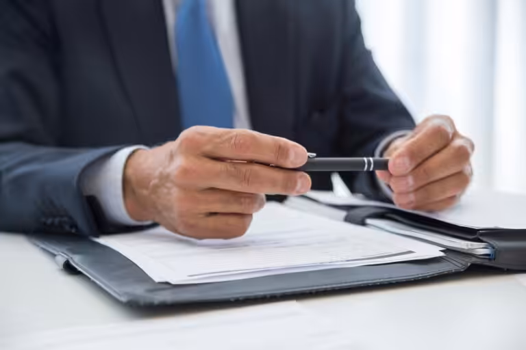 Businessman reviewing documents with pen in hand