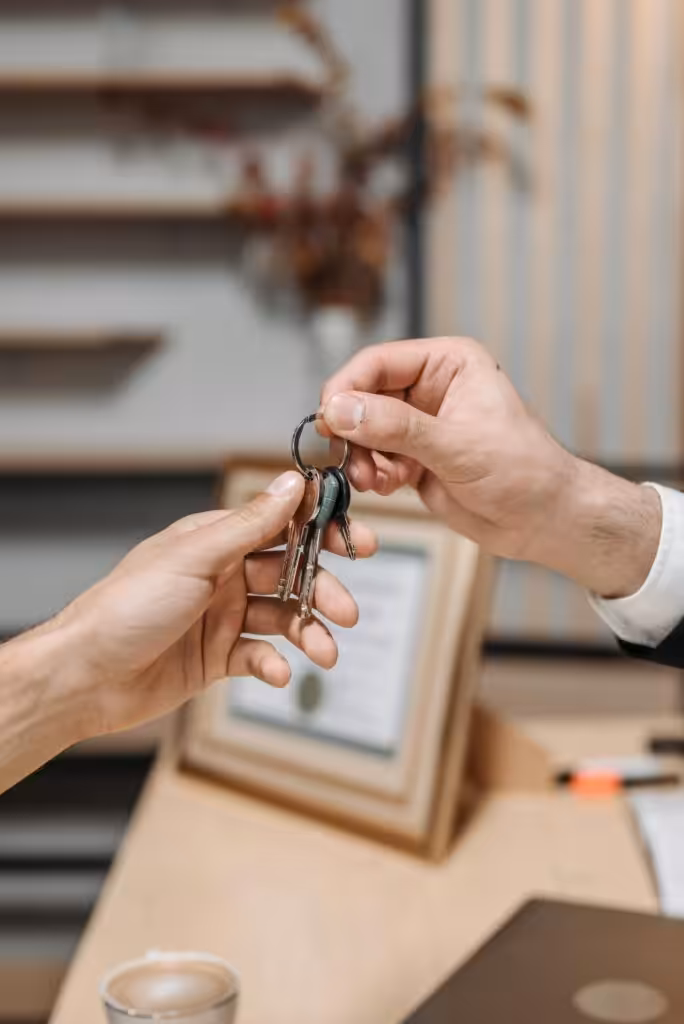 Person handing over house keys indoors