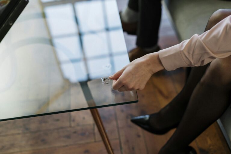 Woman placing a wedding ring on a table symbolising the end of a marriage and divorce proceedings