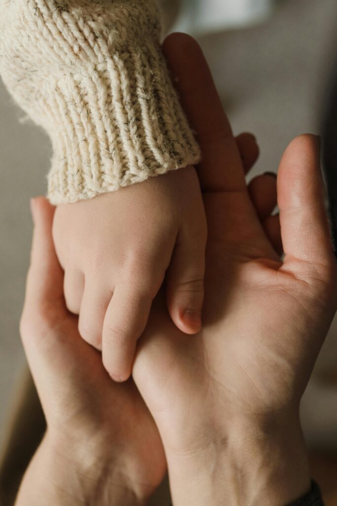 Close-up of a man and child holding hands symbolising care & protection