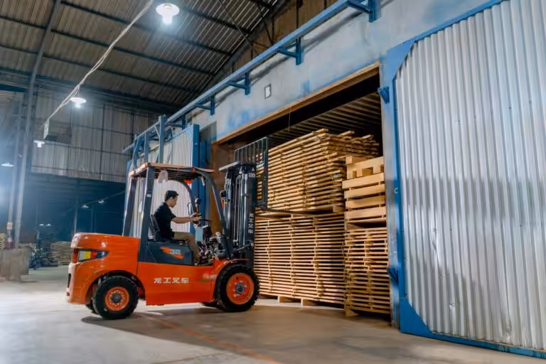Forklift moving timber pallets inside warehouse