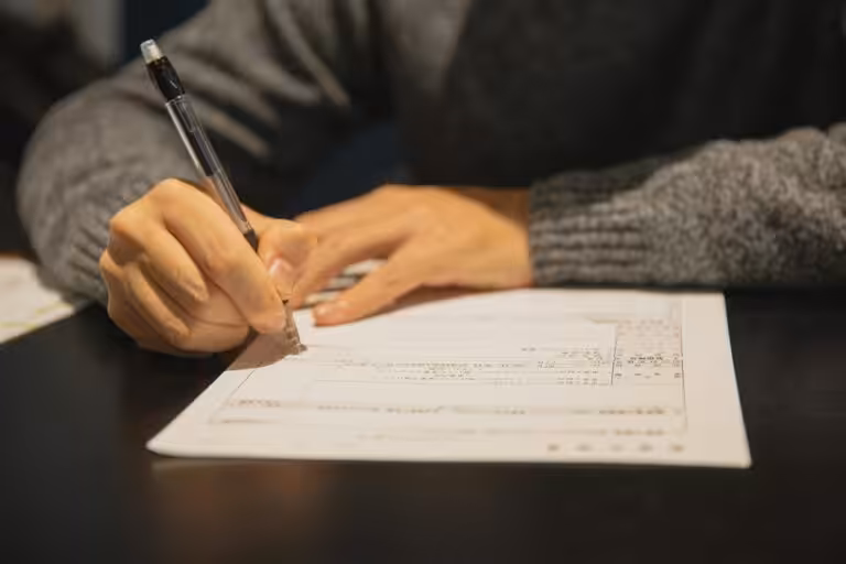 Person filling out a form with pen