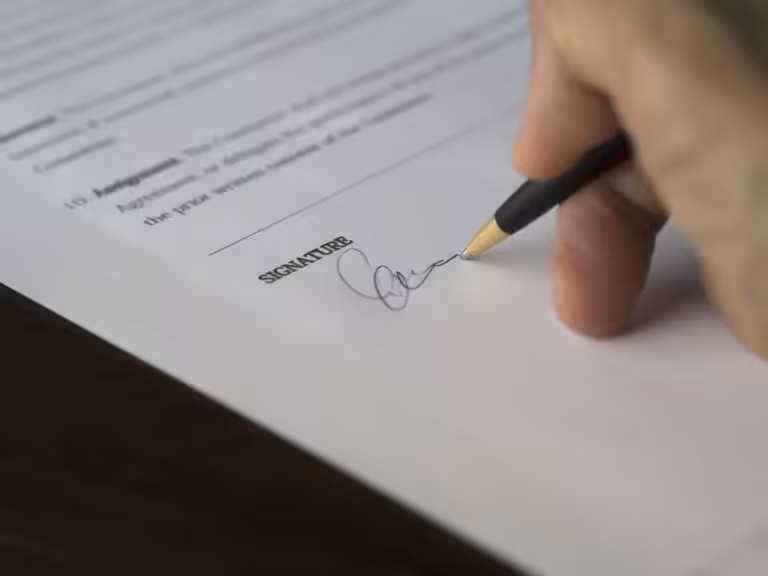 Hand signing legal document with black pen