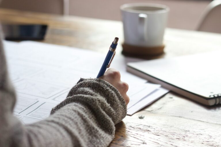 Person holding a pen and writing on legal documents with a cup in front
