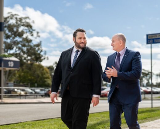 Two businessmen walking and talking outdoors in suits