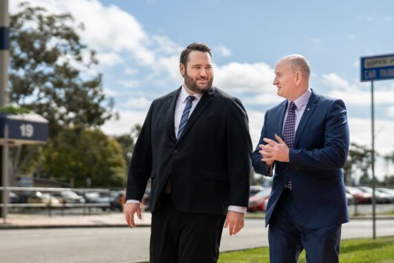 Two businessmen walking and talking outdoors in suits