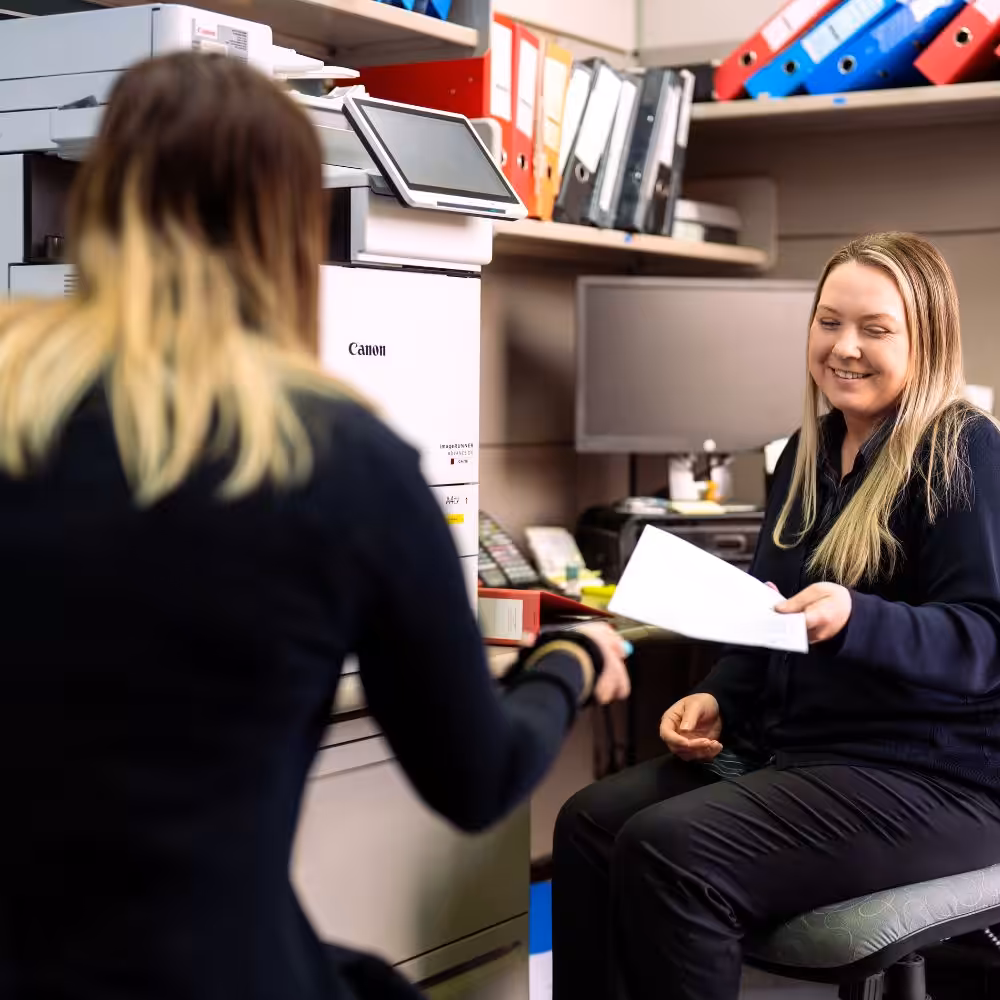 Legal team members sharing conveyancing documents near the office printer.