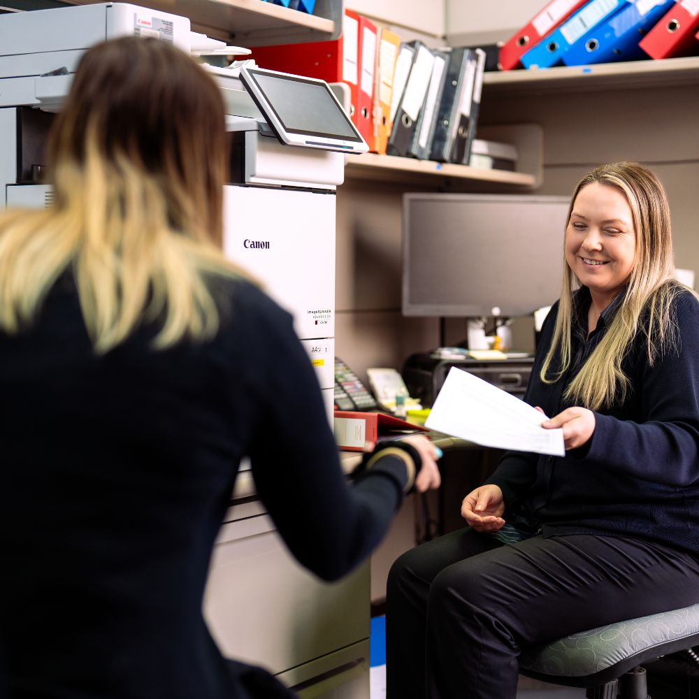 Office workers sharing documents near printer